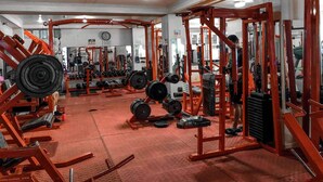 A gym with various weightlifting equipment, mirrors, and a red floor.