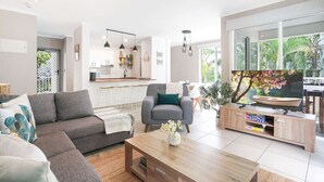 Ein modernes Wohnzimmer mit einem grauen Sofa, einem Holztisch und einem Fernseher auf einem Holzschrank.