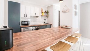 Eine moderne Küche mit weißen Schränken, einer Holz Arbeitsplatte und einer schwarzen Kaffeemaschine.