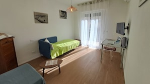 A small, well-lit room with a bed, a desk with a computer, and a television. - Bubi's Apartment, Intero Appartamento di 65mq (Livorno)