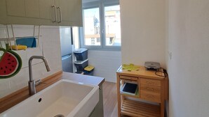 A modern kitchen with a large sink, wooden cabinets, and a small wooden table with drawers. - Bubi's Apartment, Intero Appartamento di 65mq (Livorno)