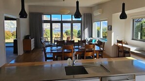 A modern kitchen with a central island, pendant lighting, and large windows offering a view of the outdoors.