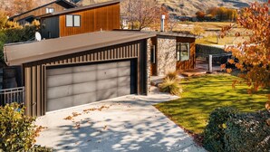 A modern two-story house with a garage, a stone exterior, and a well-maintained lawn. - Moments from That Wanaka Tree - only a 5-minute walk to That Wanaka Tree (Wānaka)