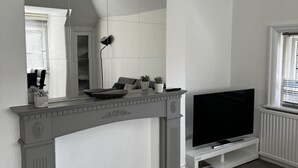 Un soggiorno moderno con camino, televisione e un grande specchio.