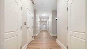 A long, narrow hallway with white doors on both sides and a wooden floor.
