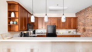A kitchen with wooden cabinets, a black refrigerator, and pendant lights.
