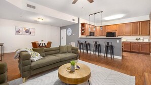 A spacious living room with a sofa, a round coffee table, and a dining area with chairs.