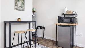 Una cocina compacta con refrigerador, microondas y una pequeña mesa con taburetes.