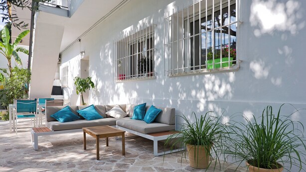 Un espace extérieur moderne aménagé avec un canapé, une table basse et des plantes en pot.