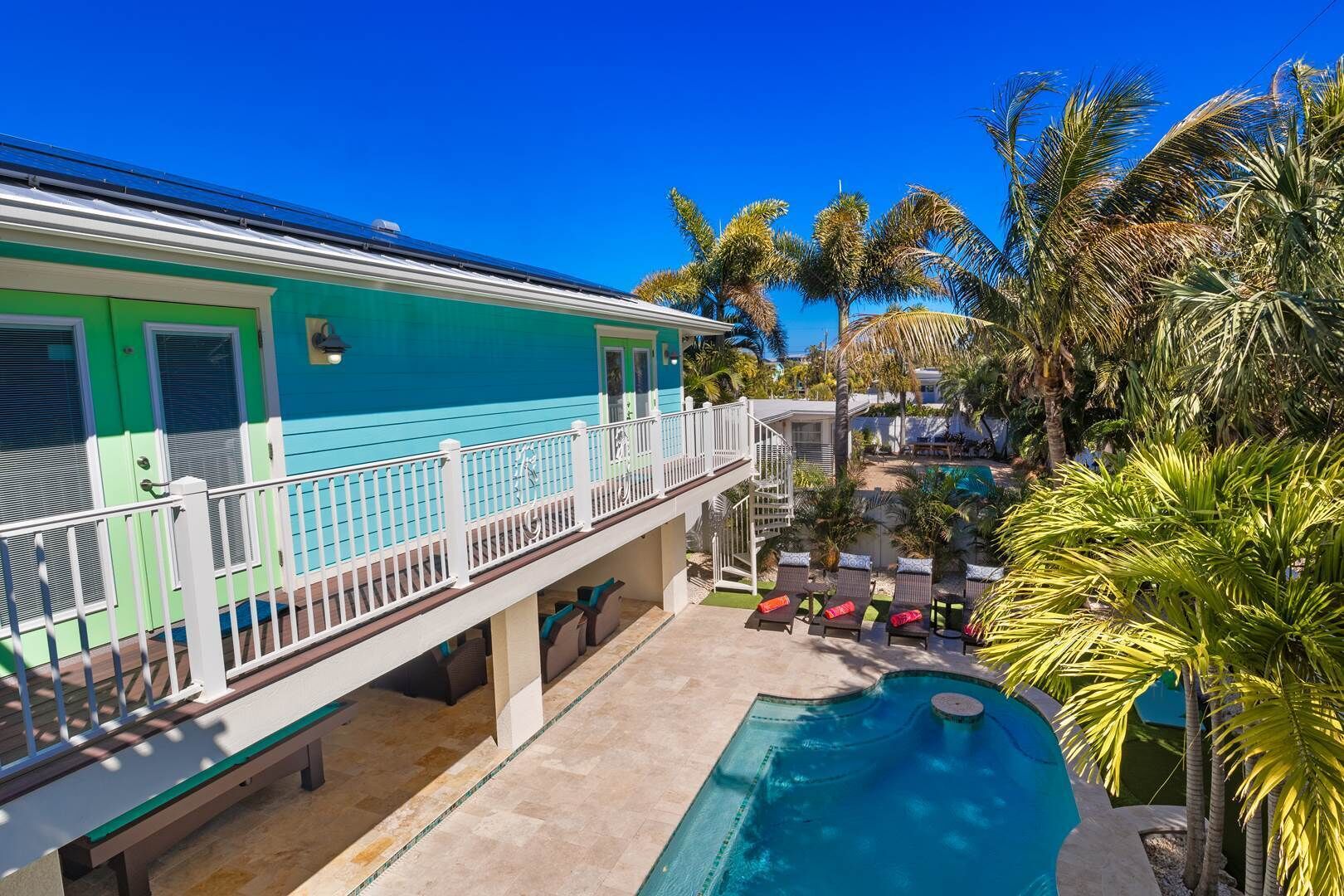 A two-story building with a balcony overlooking a swimming pool and lush greenery.