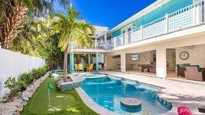 A swimming pool with a sun deck, surrounded by palm trees and a white fence. - Octopus Cottage: 1.5 Blocks to Beach, Pool & Spa by Anna Maria Life Vacation Rentals (Holmes Beach)