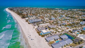 An aerial view of a coastal town with a beach, residential buildings, and a large hotel complex. - Octopus Cottage: 1.5 Blocks to Beach, Pool & Spa by Anna Maria Life Vacation Rentals (Holmes Beach)