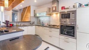 A modern kitchen with a central island, stainless steel appliances, and a wooden ceiling.