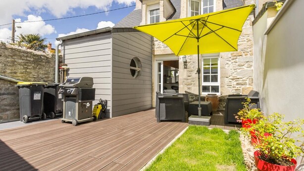 A patio with a grill, outdoor seating, and a yellow umbrella.