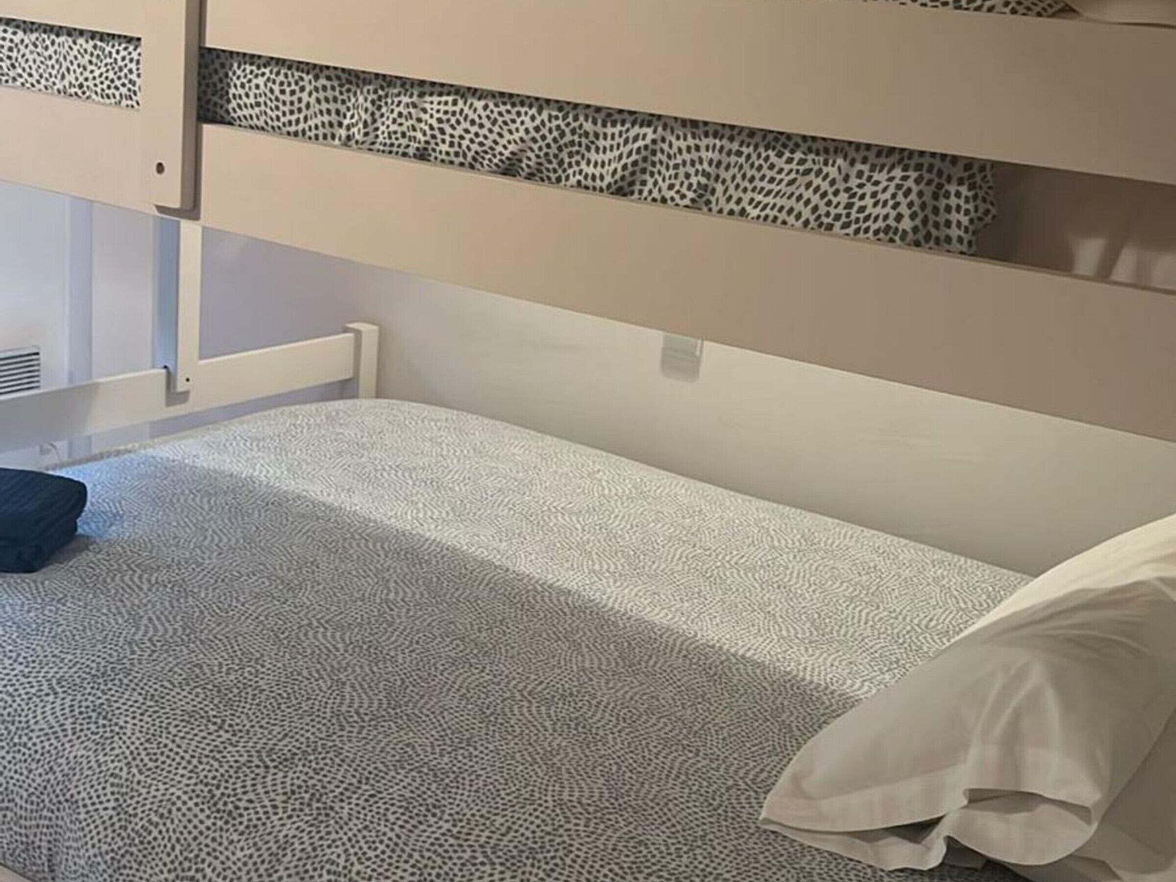 A bunk bed with a patterned bedspread and a pillow.