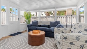 A sunlit room with a blue sofa, a patterned armchair, and a wooden coffee table.