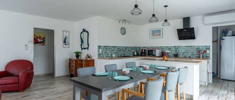 A modern kitchen with a central island, wooden flooring, and pendant lighting.