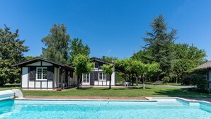 Ett tvåvåningshus med en swimmingpool på förgrunden.