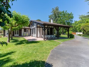 Ein traditionelles Gebäude mit überdachter Terrasse, gepflasterter Auffahrt und gepflegtem Rasen.