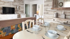 A dining area with a round table set for four, chairs, and a bench.