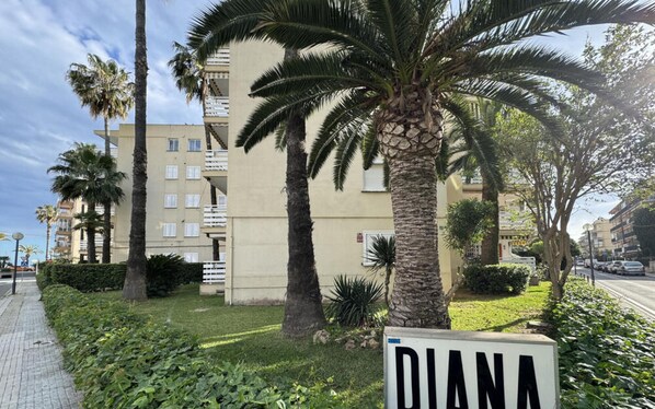 Ein Gebäude mit einem Schild, auf dem 'DIANA' steht, umgeben von Palmen und Grünpflanzen.