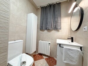 A bathroom with a toilet, a sink, a towel rack, a radiator, and a curtain. - Beachside Retreat: Family-Friendly Apartment with Terrace, Wi-Fi, and Leisure Nearby (Salou)