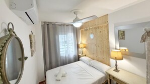 A room with a bed, bedside lamps, a mirror, and a window with curtains.