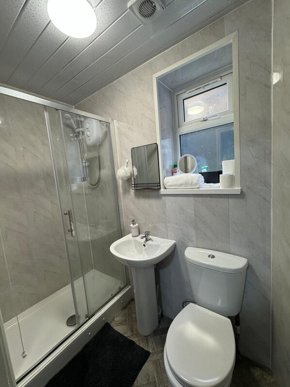 A bathroom with a glass-enclosed shower, a pedestal sink, and a toilet. - 1-bed Apart-nottingham-free Parking (Nottingham)