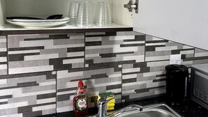 A kitchen with a stainless steel sink, a microwave, and a tiled backsplash. - 1-bed Apart-nottingham-free Parking (Nottingham)