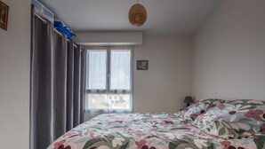 Een slaapkamer met een bed, een raam en een hanglamp.