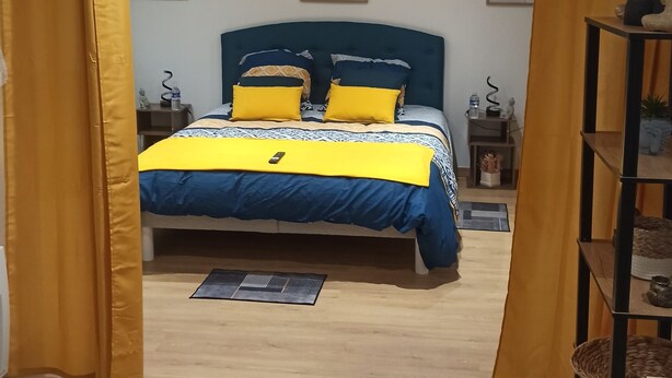 A bedroom with a bed, yellow curtains, a headboard, and artwork on the walls. - Maison le Laos (Les Ageux)