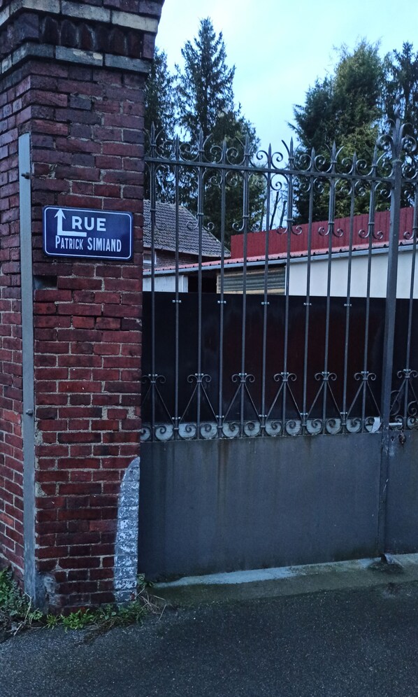 A brick wall with a metal gate and a sign that reads "Rue Patrick Simiand."