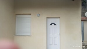 A beige building with a white door and a window with closed shutters. - Maison le Laos (Les Ageux)