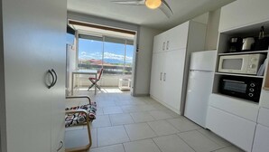 Une cuisine moderne avec des meubles blancs, un réfrigérateur, un four à micro-ondes et un ventilateur de plafond.