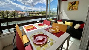 Un coin repas avec une table dressée pour deux personnes, un canapé et un tableau accroché au mur.