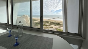 A room with a large window overlooking a beach and a pier.