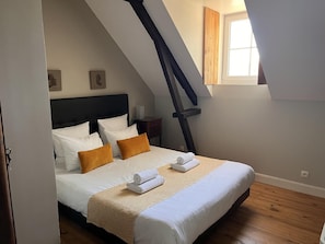 A bedroom with a bed, pillows, a nightstand, a window, and a sloped ceiling.