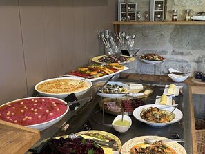 A buffet with various dishes, including salads, pasta, and a large bowl of soup.