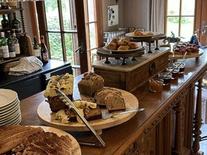 A buffet with various food items including cakes, pastries, and bread.