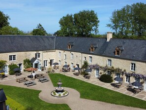 A courtyard with outdoor seating, a fountain, and stone buildings. - Charming house near Utah Beach, pets allowed (Sainte-Marie-du-Mont)