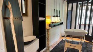 A bathroom with a wooden door, a white sink, a black rug, and a wooden bench. - Charming house near Utah Beach, pets allowed (Sainte-Marie-du-Mont)
