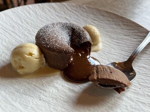 Un dessert composé d’un fondant au chocolat, de boules de glace à la vanille et d’une cuillère de sauce au chocolat.
