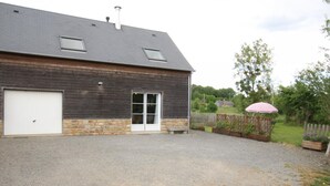 Un bâtiment à deux étages avec une allée en gravier, une porte de garage blanche et une clôture en bois.