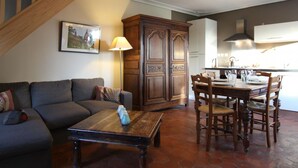 A living room with a sofa, coffee table, and dining area with chairs and a table. - Charming house with fireplace and pets allowed near Utah Beach (Sainte-Marie-du-Mont)