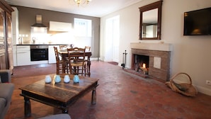 A spacious living room with a fireplace, a dining area, and a kitchen. - Charming house with fireplace and pets allowed near Utah Beach (Sainte-Marie-du-Mont)