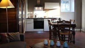 A modern kitchen with a dining area, featuring a stove, oven, and a window providing natural light. - Charming house with fireplace and pets allowed near Utah Beach (Sainte-Marie-du-Mont)