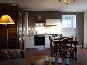 A modern kitchen with a dining area, featuring a stove, oven, and a window providing natural light.