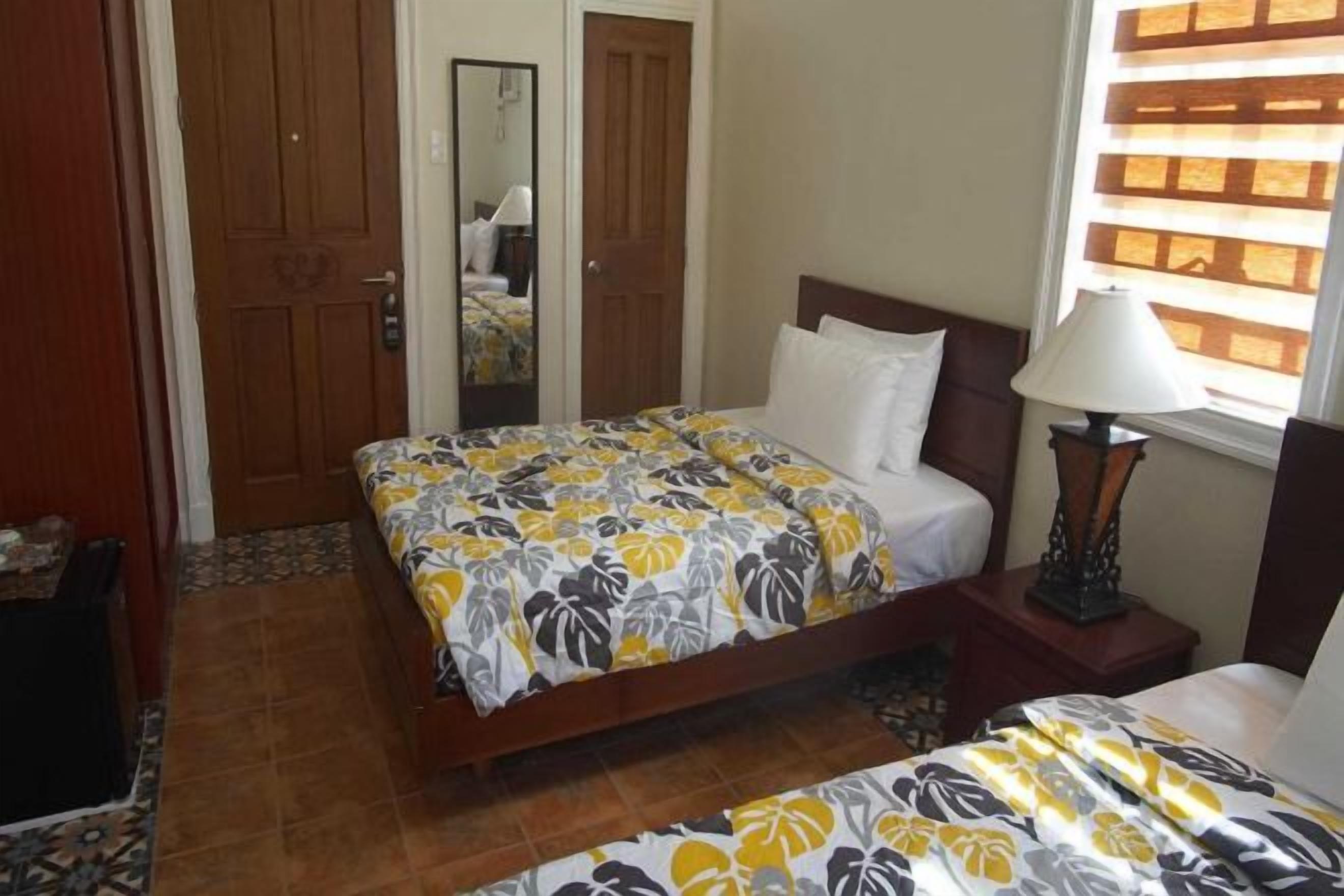 Un dormitorio con una cama, una mesita de noche, una lámpara y una ventana con persianas.
