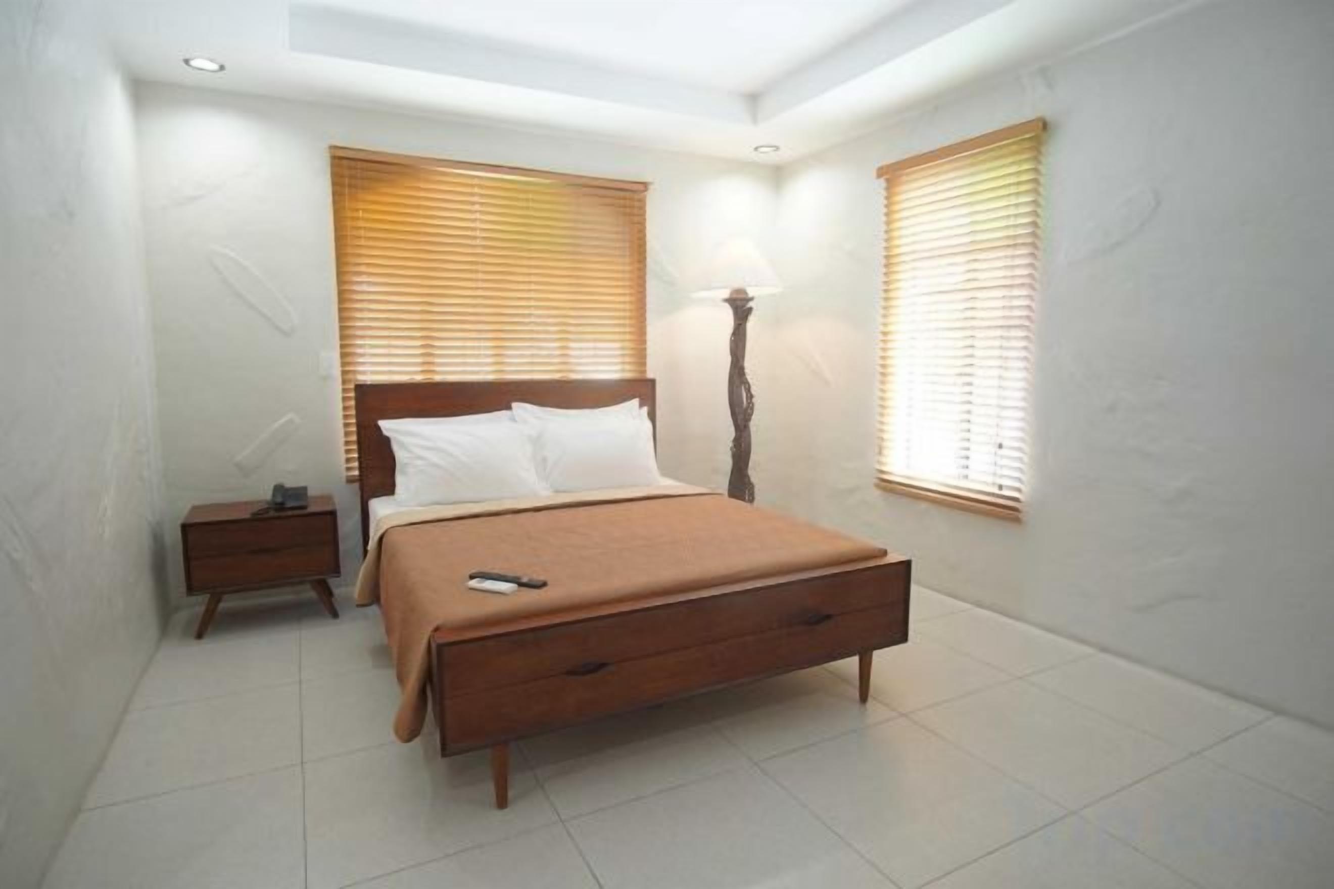 A bedroom with a bed, bedside tables, and a lamp.