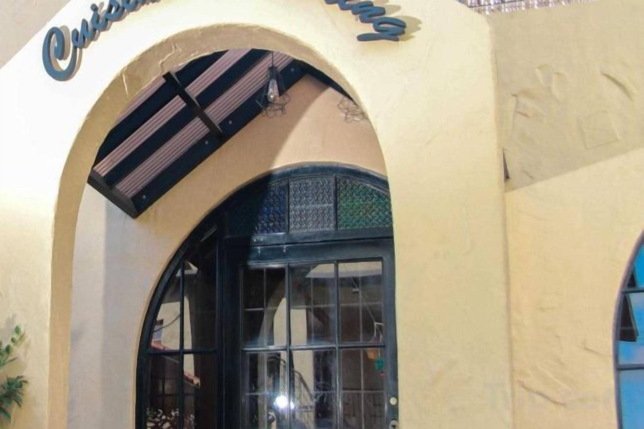 Une entrée en arc surmontée d’une enseigne.